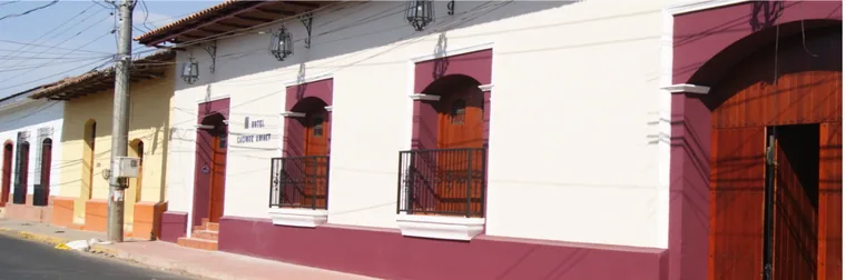 La fachada blanca del hotel en la calle, con el portón de entrada y plantas en las ventanas